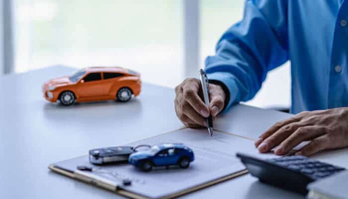 Car insurance costs | tycoonstory media Driver reviewing an auto insurance policy and costs as rising auto premiums affect vehicle coverage expenses.