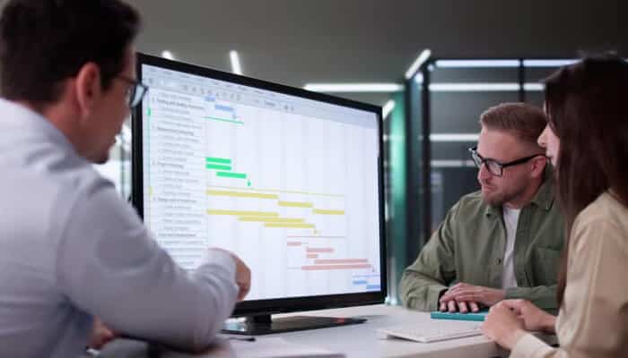 Best for fast, visual drag-and-drop gantt scheduling with real-time collaboration | tycoonstory media Team members reviewing project timelines on a computer using project scheduling tools to organize tasks, deadlines, and workflow planning.