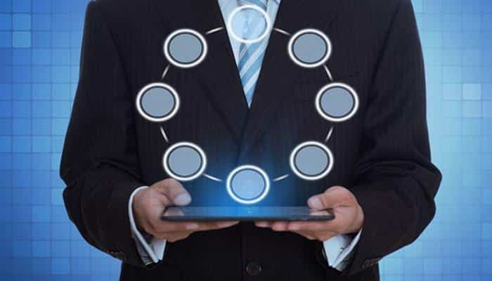 How to choose the right business structure? | tycoonstory media Businessperson in a suit holds a tablet with a glowing circular network of connected nodes above it, representing digital connectivity.