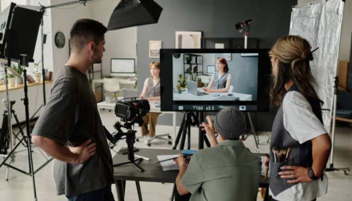 How product video generation can answer the questions that block a purchase 1 | tycoonstory media Video shoot in a studio: camera operator and crew monitor a framed shot of a seated host on a monitor.