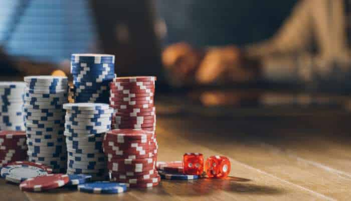 How to compare the five sister brands under syarikat4 group and pick your best no-deposit start in 2026 1 | tycoonstory media Stacks of blue, white, and red poker chips on a wooden casino table with two red dice nearby.