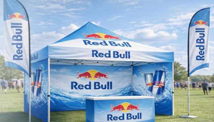 When is a branded canopy a good investment? | tycoonstory media Red bull promotional tent with banners and logo in a grassy field on a sunny day