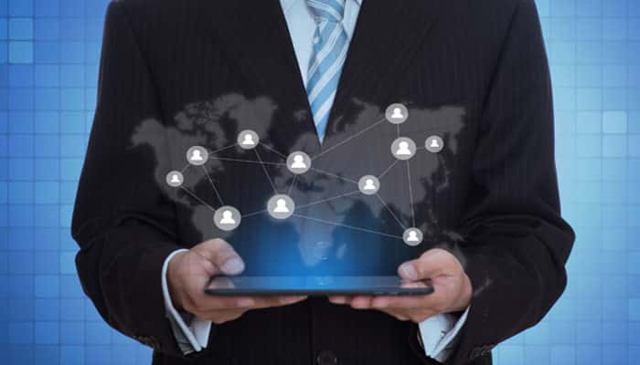 Map every customer touchpoint | tycoonstory media Man in a suit holding a tablet, with a global network of connected user icons overlaid on a blue tech background.