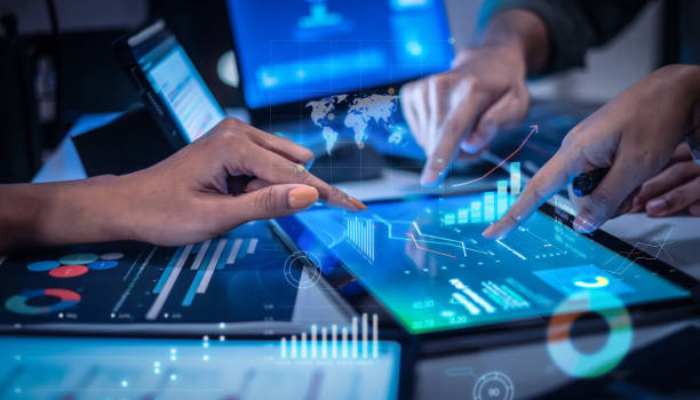 Loyalty roi explained the way a cfo actually wants to hear it 1 | tycoonstory media Two people analyze data on transparent tablet screens with blue holographic charts and a world map overlay.