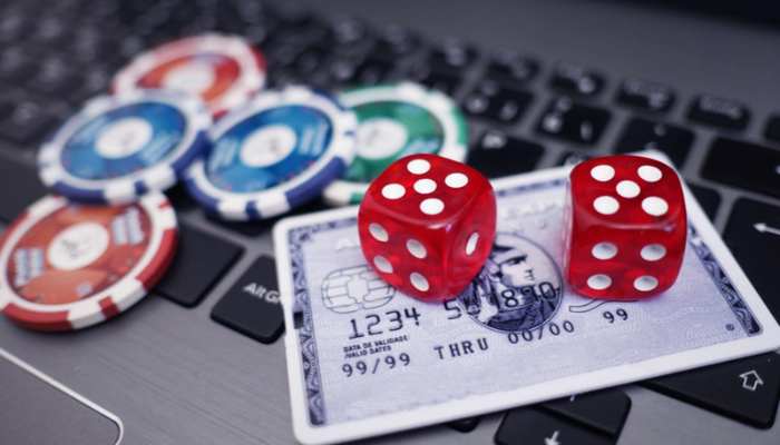 Real-money online casino games 4 | tycoonstory media Two red dice rest on a credit card over a laptop keyboard, with poker chips in the background.