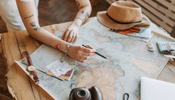 Travel - tycoonstory | tycoonstory media Magfusehub com travel guide concept showing a traveler planning a journey with a world map, notebook, camera, and travel essentials for exploring destinations and travel insights