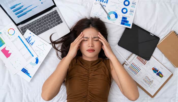 12 ways to improve startup sleep without losing productivity | tycoonstory media Startup sleep challenges illustrated through an exhausted entrepreneur surrounded by business reports and devices, showing how stress, workload, and poor rest can impact founder productivity and mental clarity.