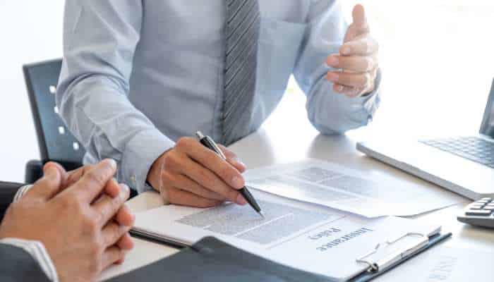 When should you review your term insurance policy 1 | tycoonstory media Two professionals review and sign a contract at a desk with a laptop nearby.
