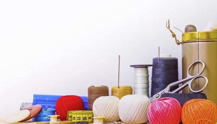Consider supplier reputation | tycoonstory media Assorted sewing supplies on a table: colorful yarn balls, spools of thread, scissors, a tape measure, and a metal canister in the background.
