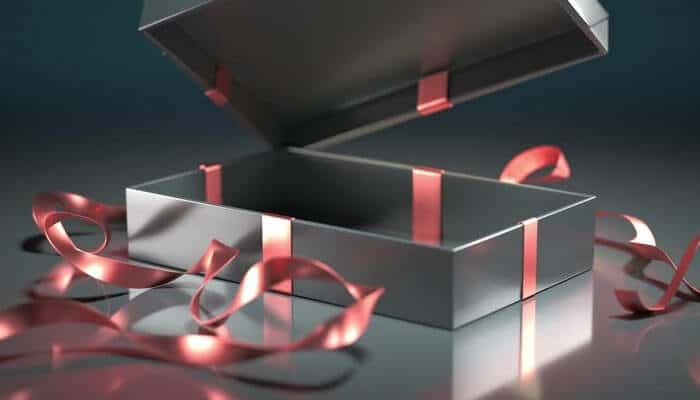 Premium packaging improves gift appeal | tycoonstory media Open metallic silver gift box with pink ribbons on a reflective surface.