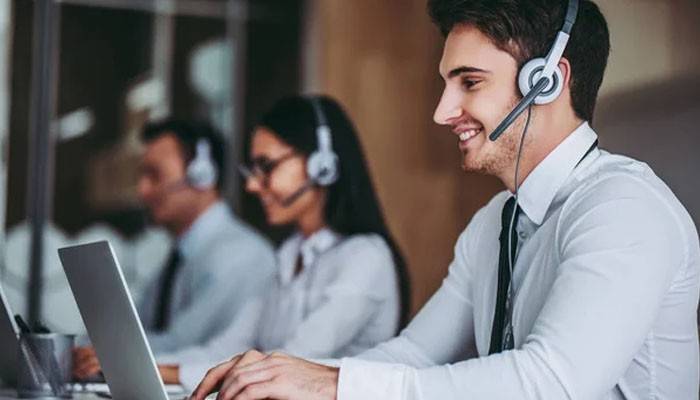 Ringcentral ringwem | tycoonstory media Customer support agents wearing headsets and working at laptops in a call center, smiling and assisting customers.