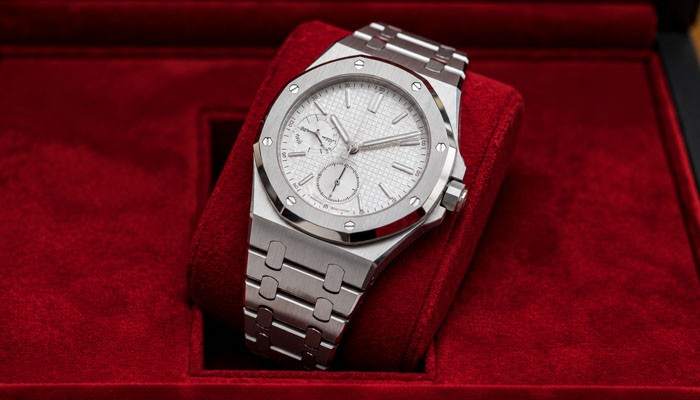 Now look beyond the watch itself | tycoonstory media Stainless steel luxury wristwatch with a textured white dial placed on a red velvet display box.