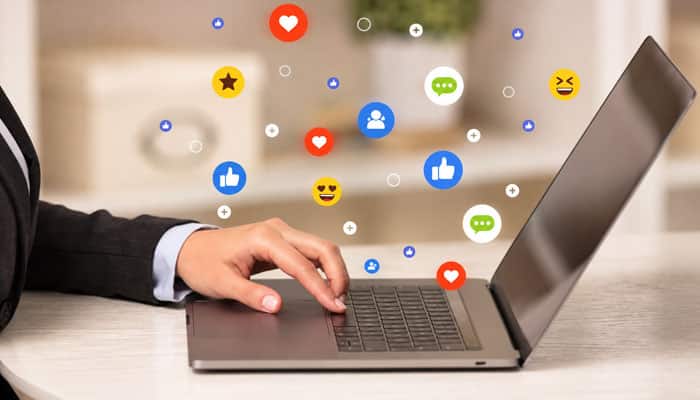 | tycoonstory media Hands typing on a laptop with colorful social media icons floating above the keyboard, portraying online engagement.