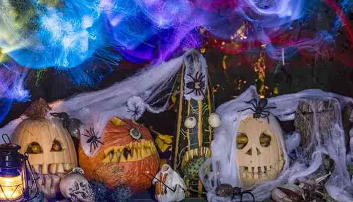 Whats new at spirit halloween in 2026 - tycoonstory | tycoonstory media Spirit halloween spooky display featuring carved pumpkin skulls, creepy spiders, hanging cobwebs, skeleton props, and colorful haunted house lighting.
