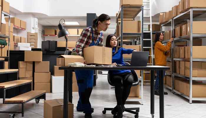 Where do target employees work - tycoonstory | tycoonstory media Warehouse employees organizing packages and inventory, illustrating "about how many employees does target corporation employ? " across supply chain operations.